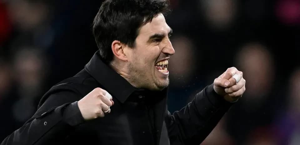 Entrenador celebrando con puños apretados en el banquillo