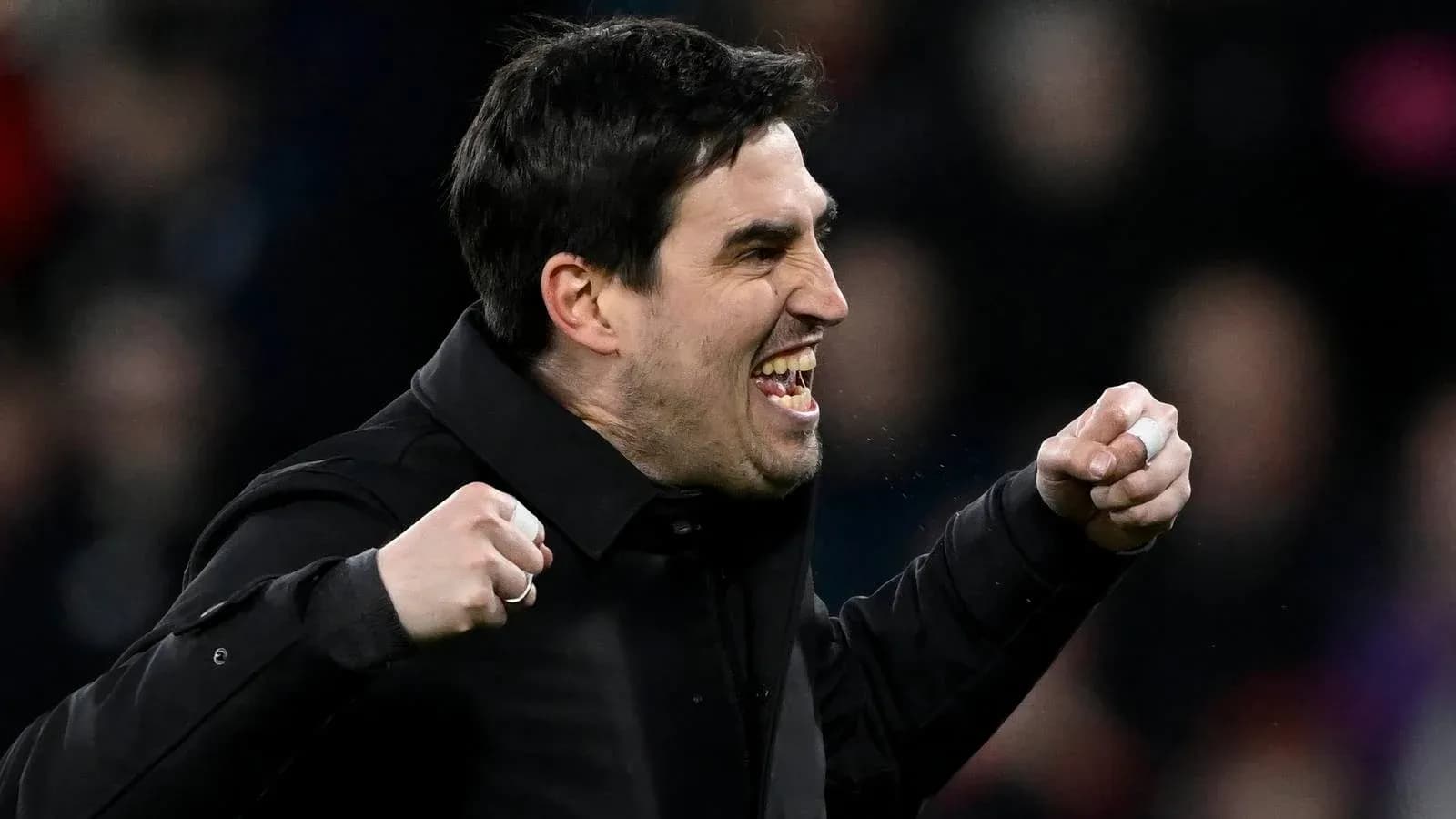 Entrenador celebrando con puños apretados en el banquillo