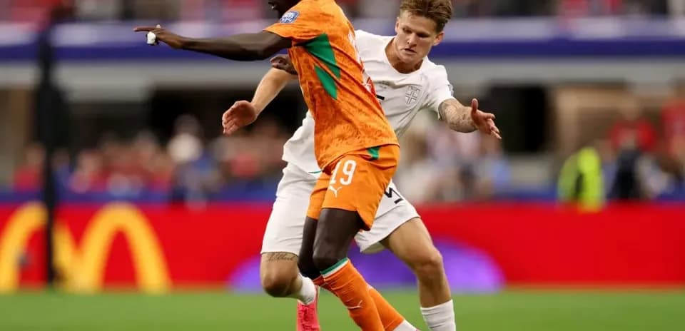 Jugador de Costa de Marfil driblando ante rival inglés