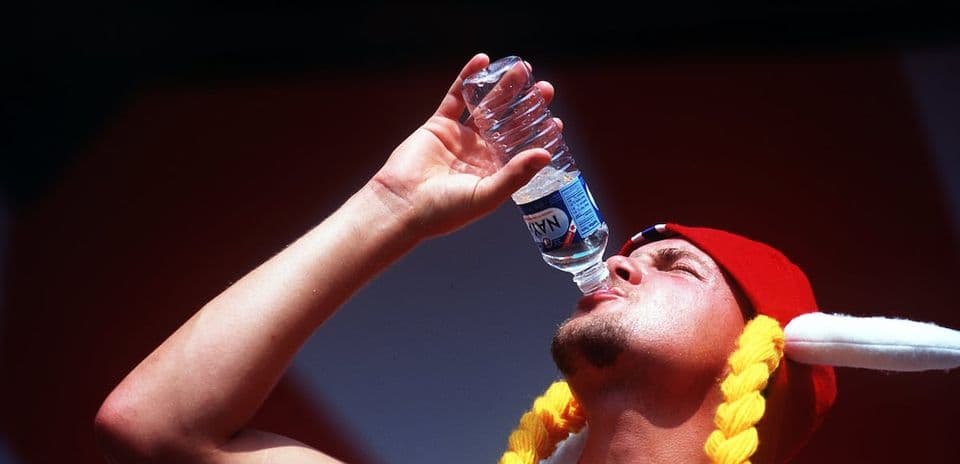 Hombre bebiendo agua de una botella en evento