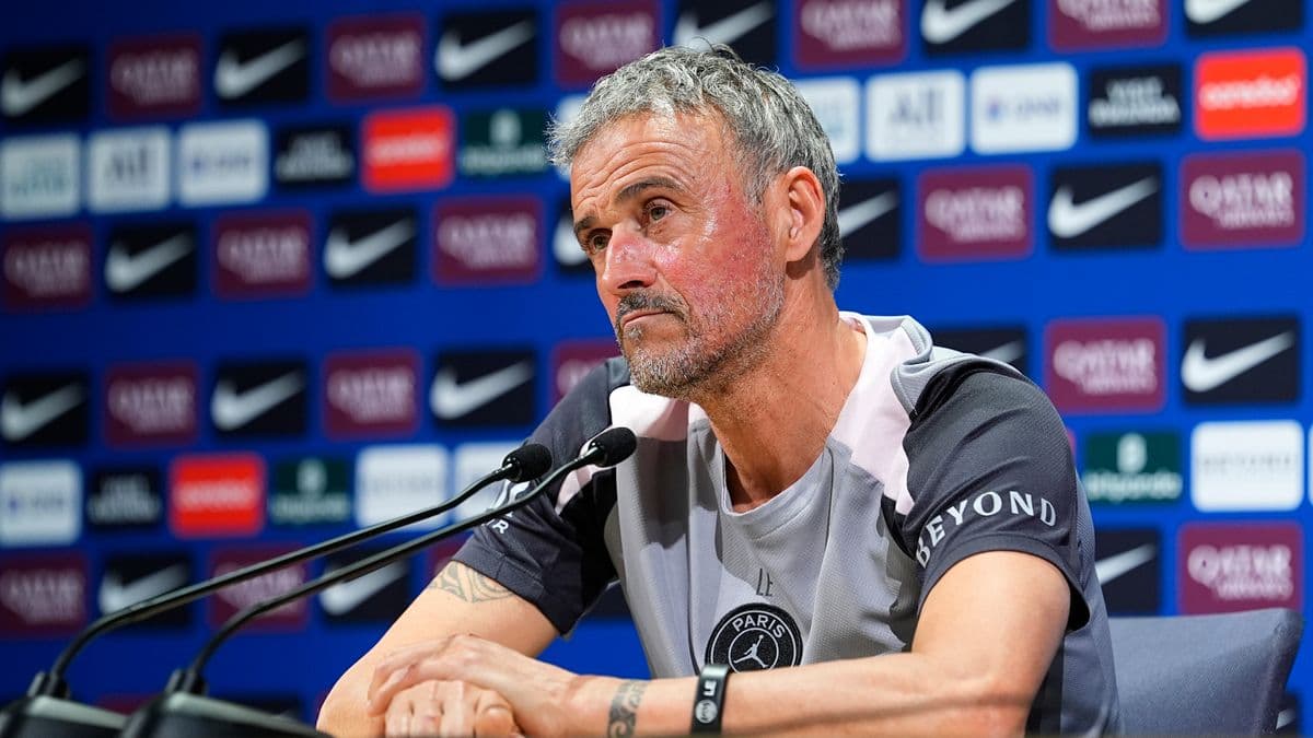 Entrenador en conferencia de prensa con fondo publicitario