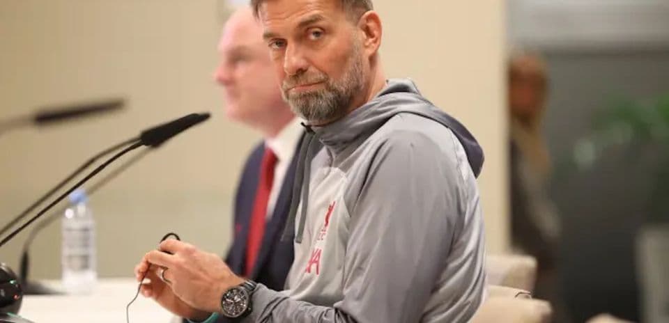 Entrenador en conferencia de prensa sentado con micrófono