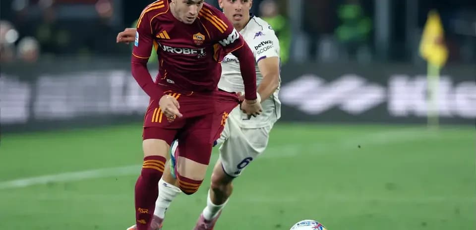 Jugador de Roma driblando mientras es seguido por adversario