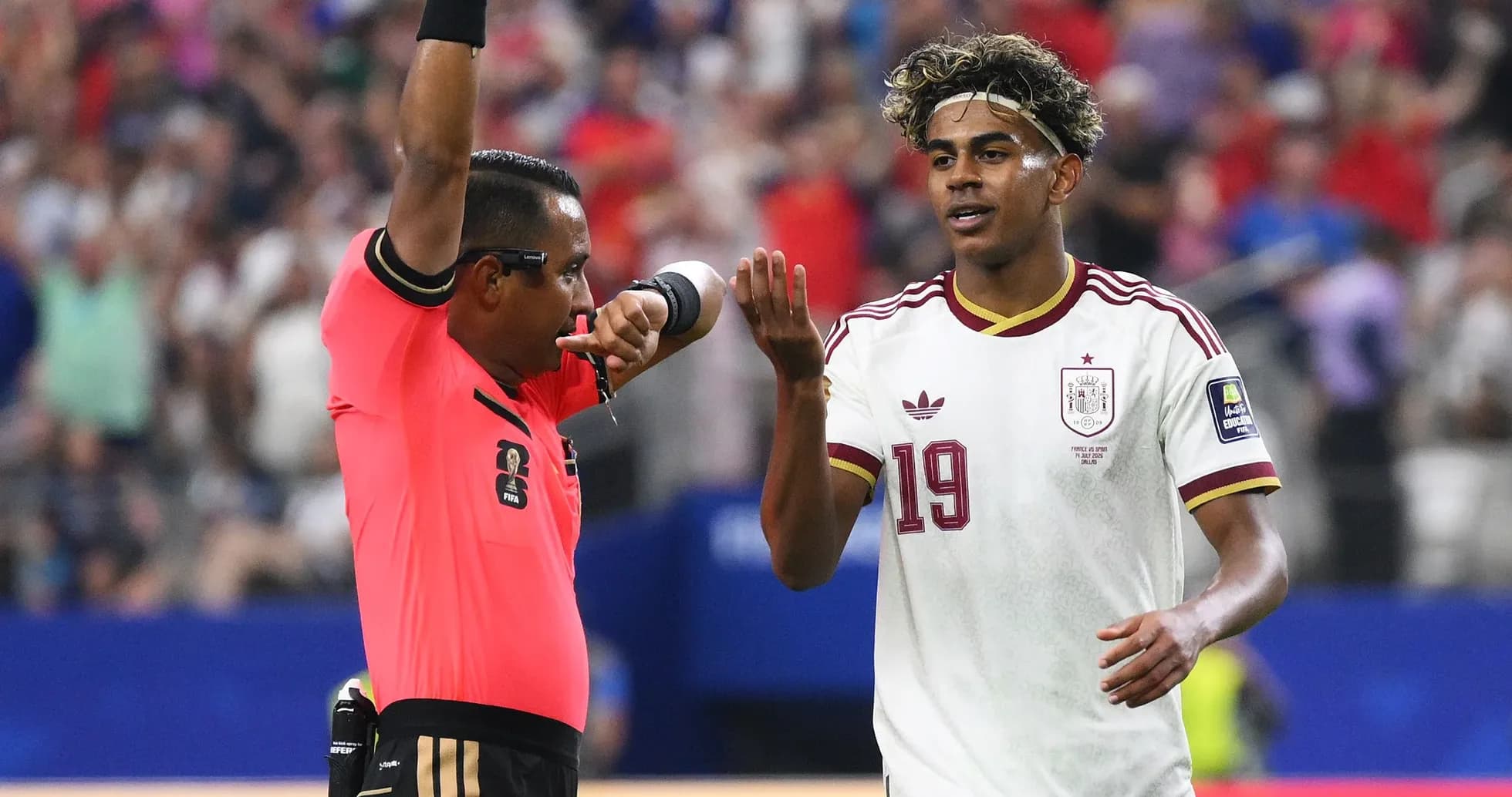 Árbitro mostrando tarjeta mientras jugador consulta