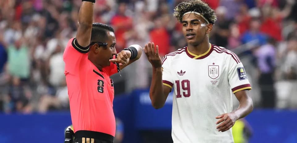 Árbitro mostrando tarjeta mientras jugador consulta