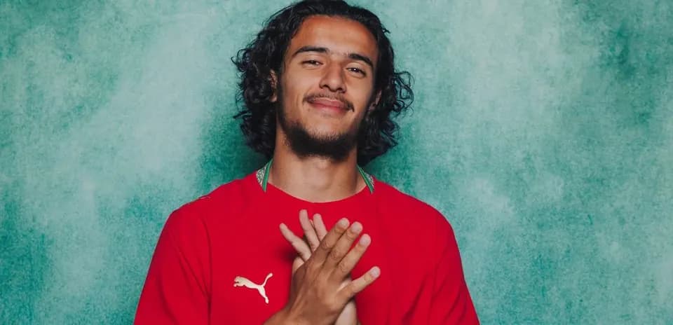 Jugador posando con camiseta roja frente a fondo verde