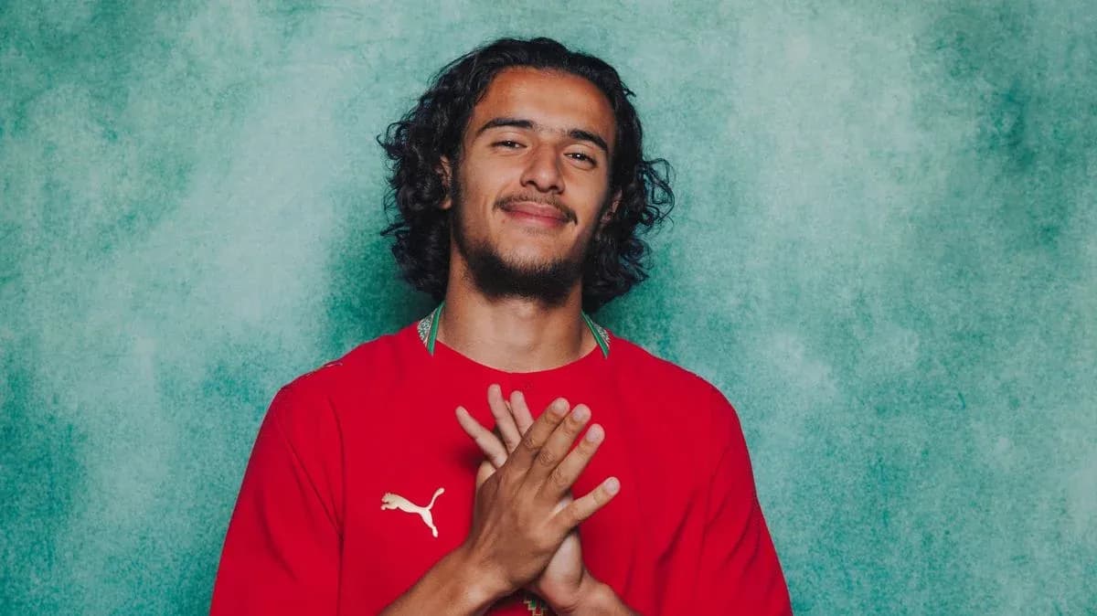 Jugador posando con camiseta roja frente a fondo verde