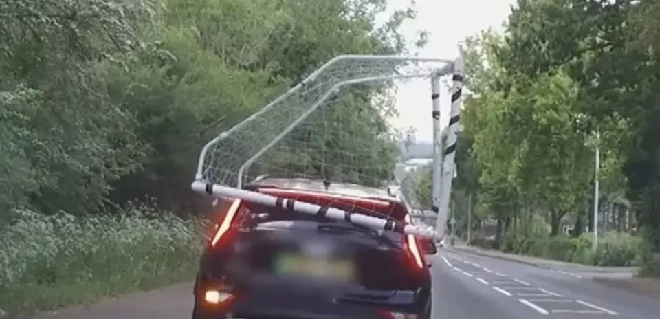 Coche transportando una portería de fútbol en carretera