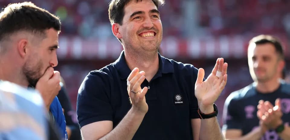 Entrenador aplaudiendo junto a jugadores en el estadio