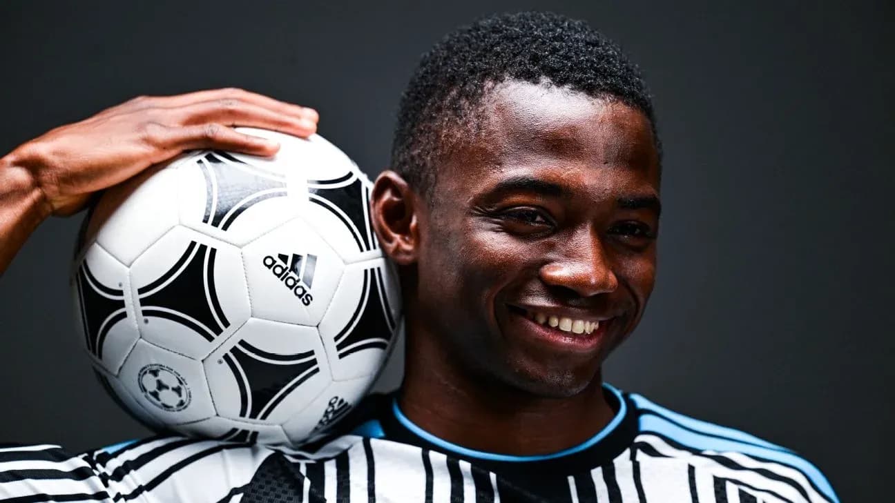Jugador sosteniendo un balón de fútbol sonriendo