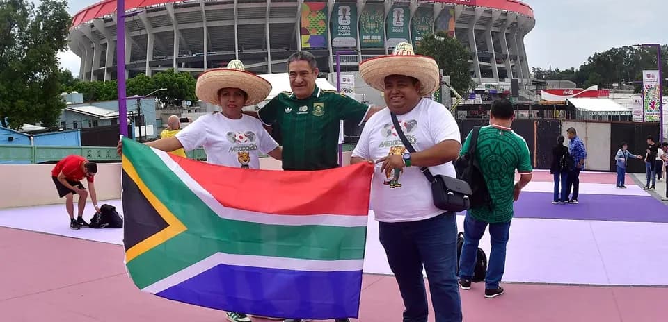 Aficionados sosteniendo bandera de Sudáfrica frente al estadio