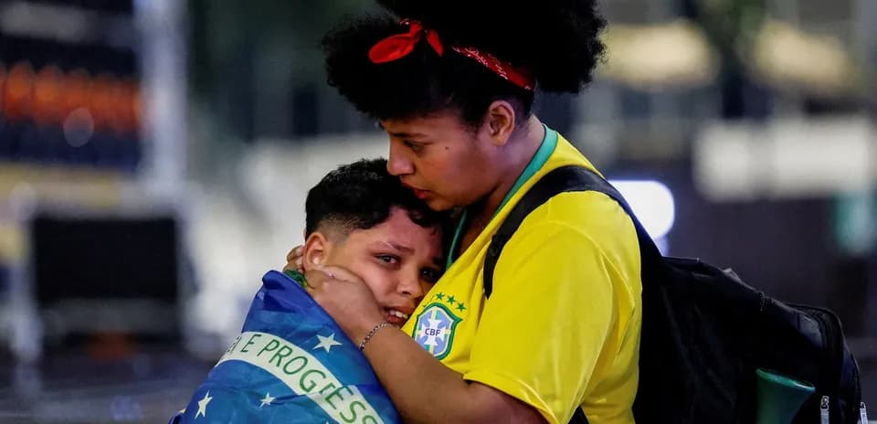 Mujer abraza a niño envuelto en bandera brasileña