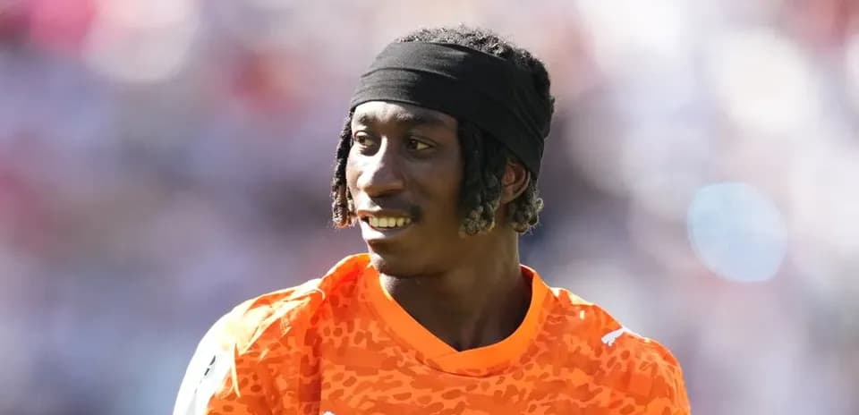 Portero con camiseta naranja sonriendo en el campo
