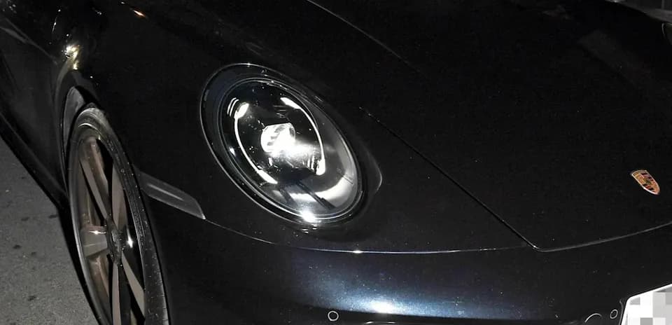 Dos personas dentro de un Porsche negro en la noche