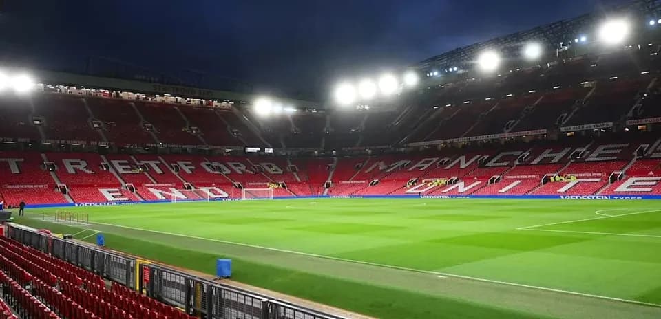 Estadio Old Trafford con luces encendidas y césped
