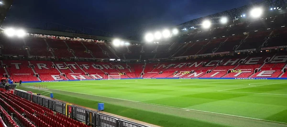 Estadio Old Trafford con luces encendidas y césped