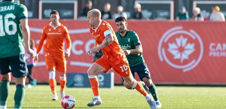 Jugador corriendo con balón en partido de fútbol