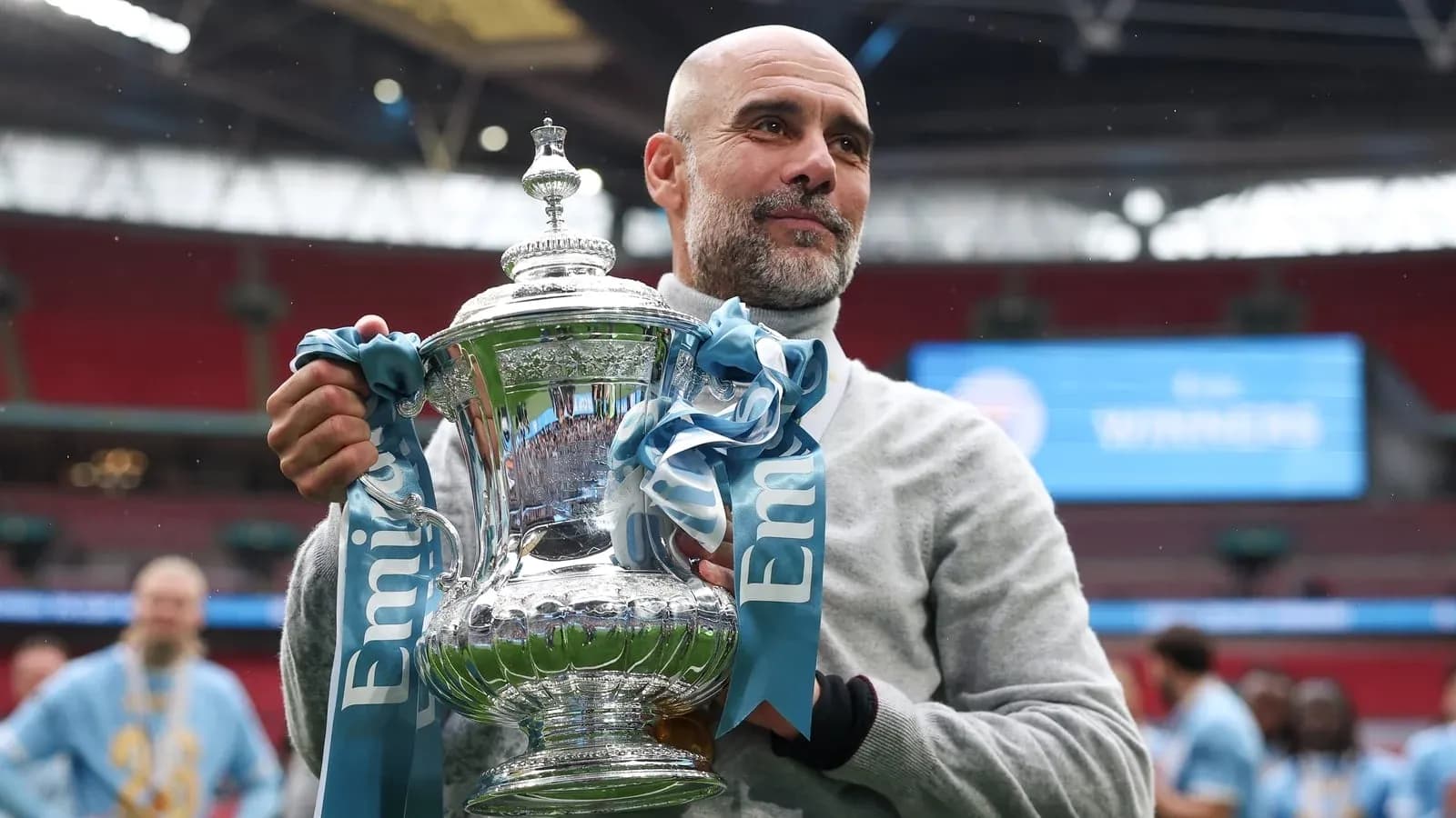 Entrenador sosteniendo trofeo en Wembley