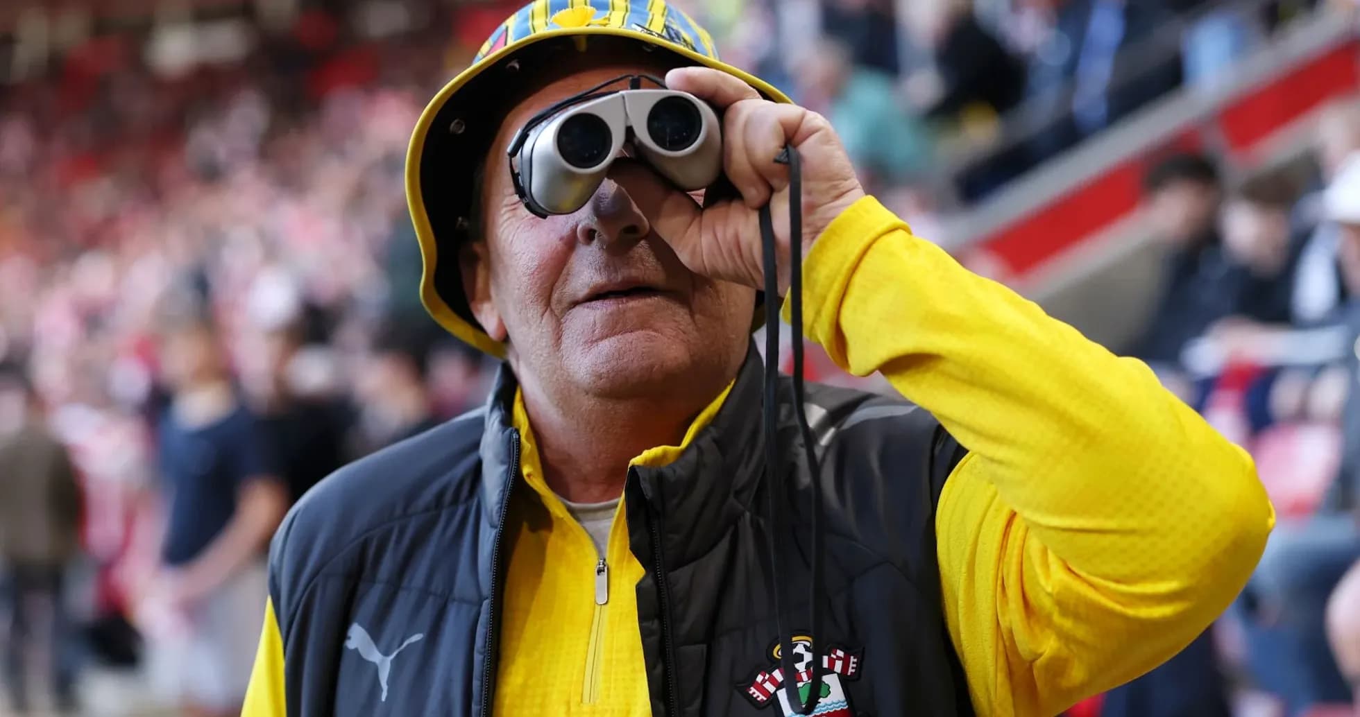 A fan using binoculars at a football match