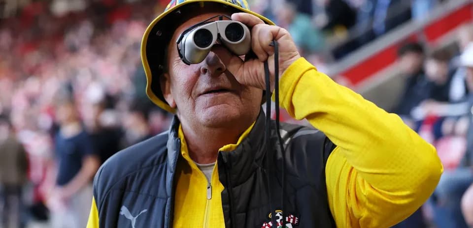 A fan using binoculars at a football match