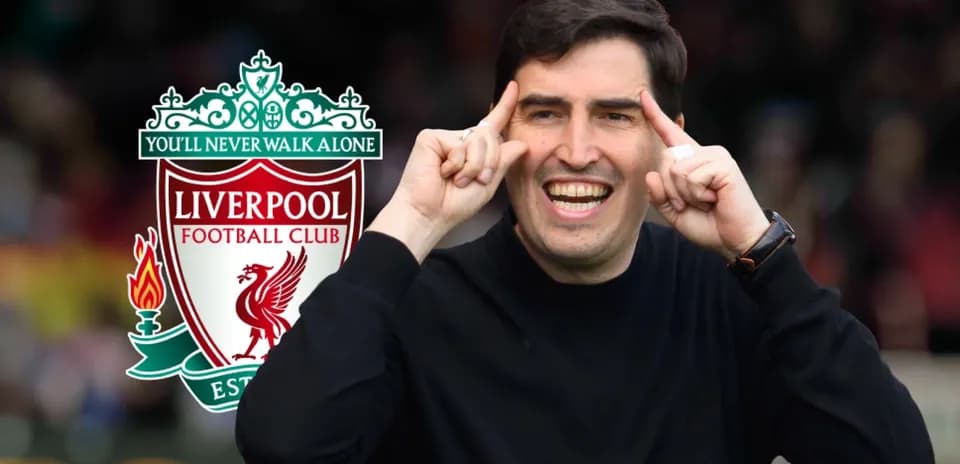 Entrenador sonriente gesticulando junto al logo de Liverpool