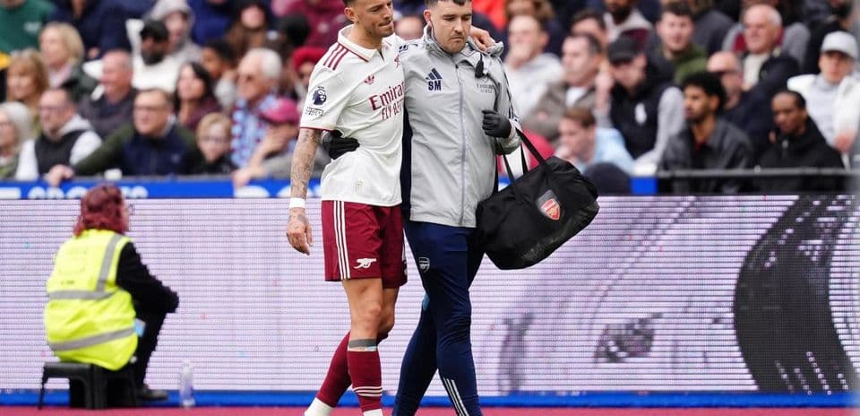 Jugador de Arsenal siendo ayudado por médico en el campo