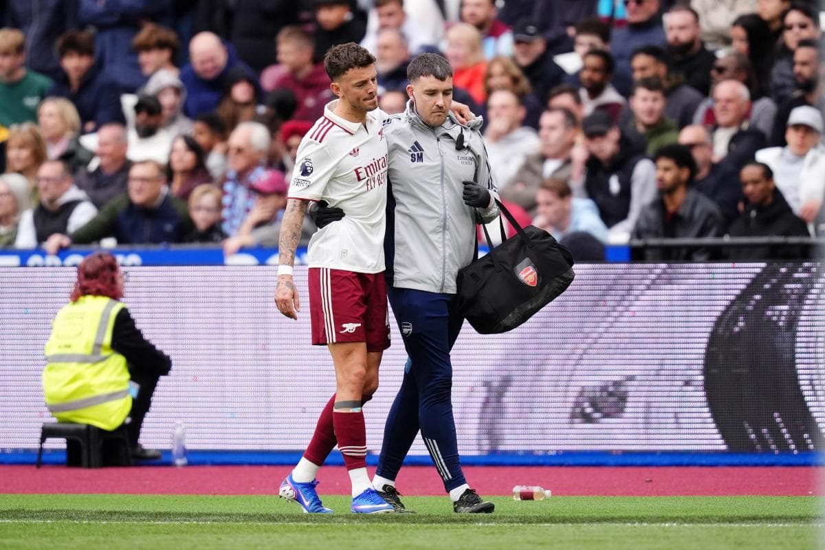 Jugador de Arsenal siendo ayudado por médico en el campo