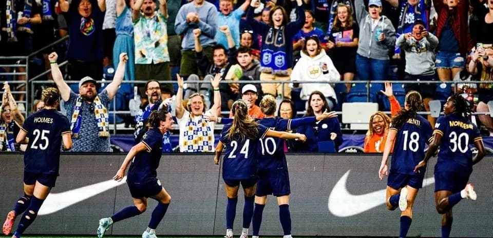 Jugadoras celebrando un gol con aficionados