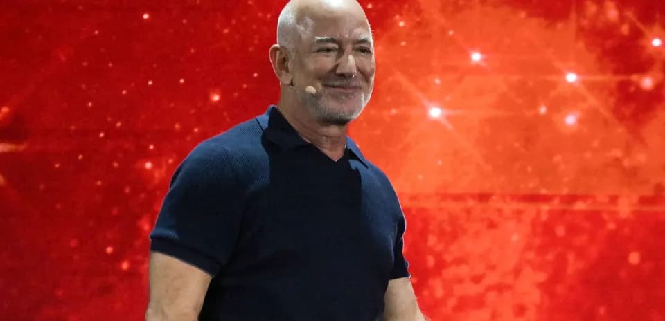 Hombre sonriente en un escenario con fondo rojo