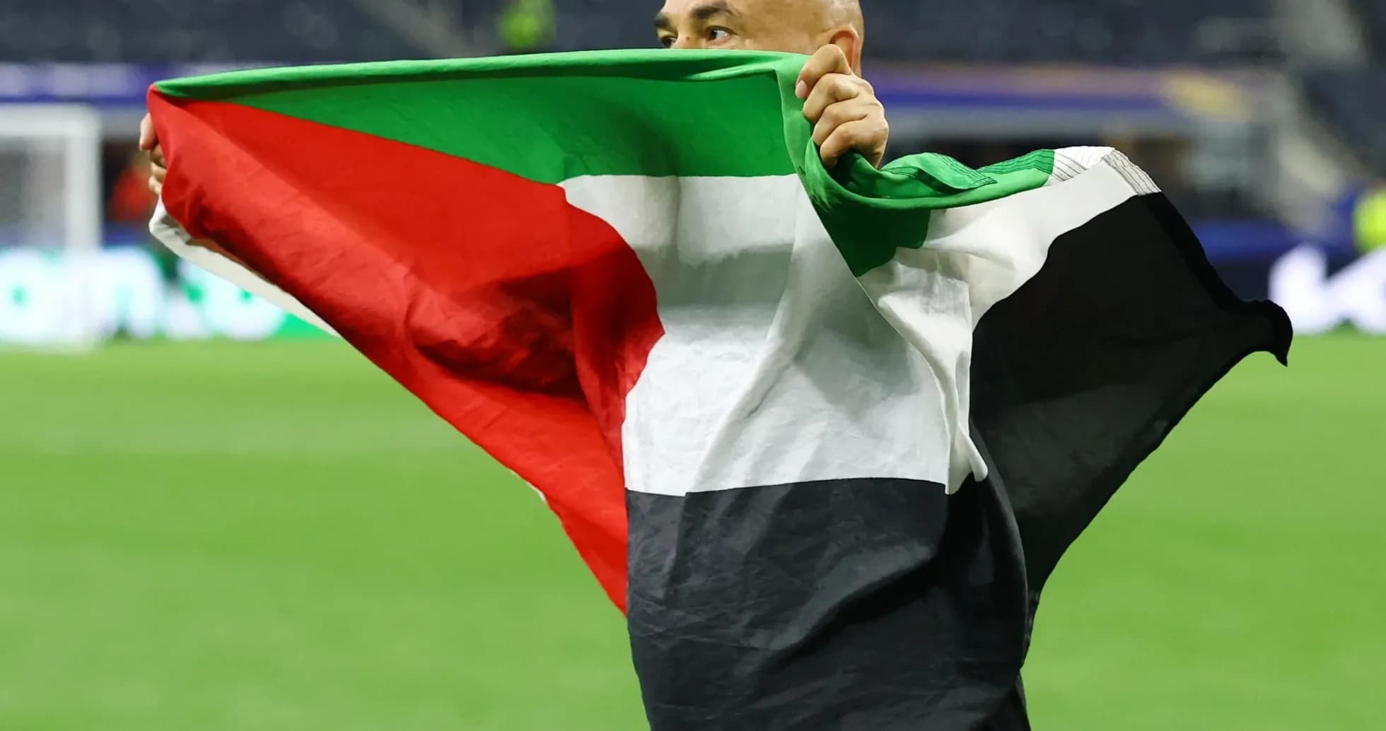 Hombre sosteniendo una bandera en el campo de juego