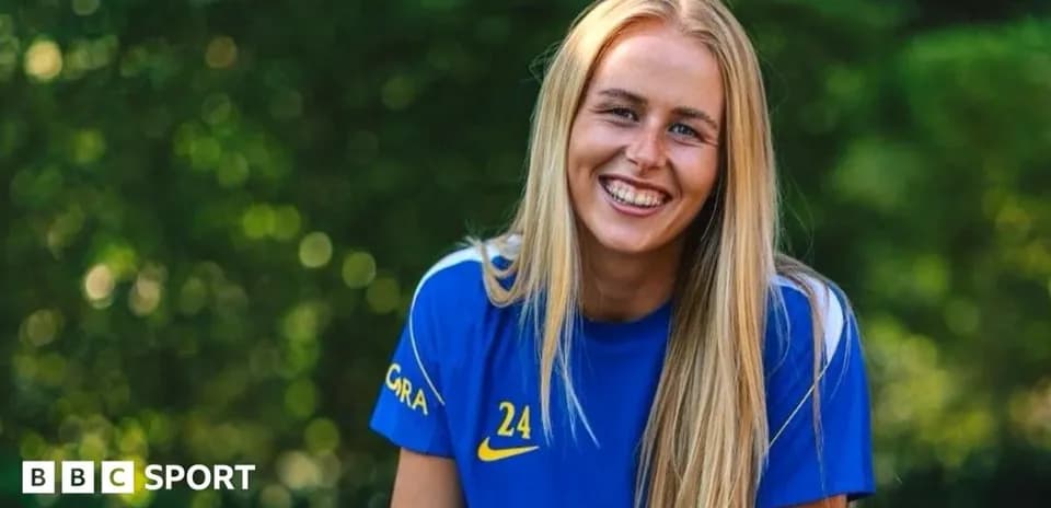 Jugadora sonriendo en uniforme azul de fútbol