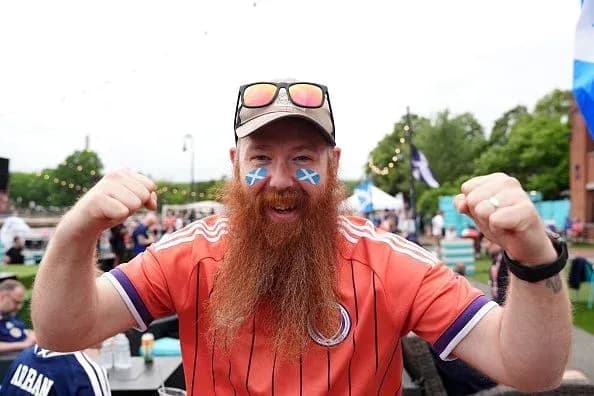 A fan celebrating with painted face and orange jersey