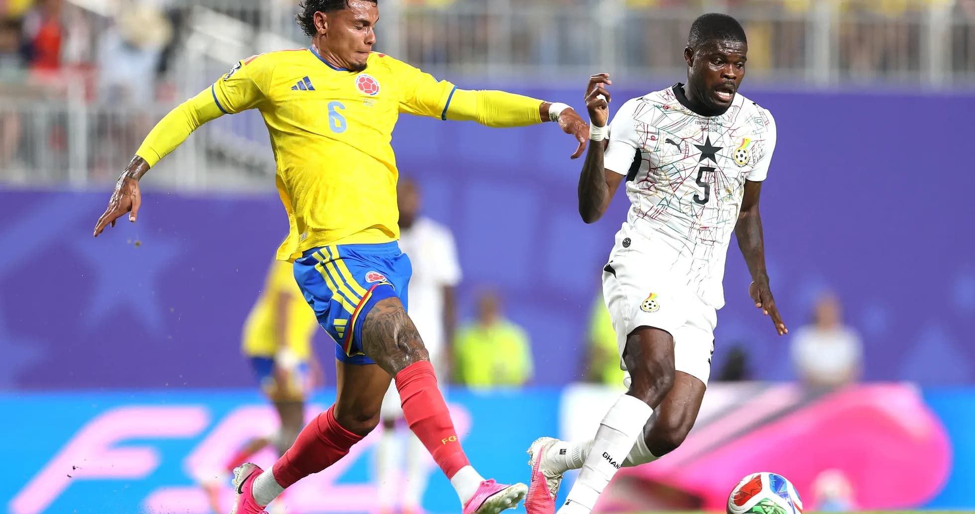 Jugador colombiano persigue a su oponente ghanés
