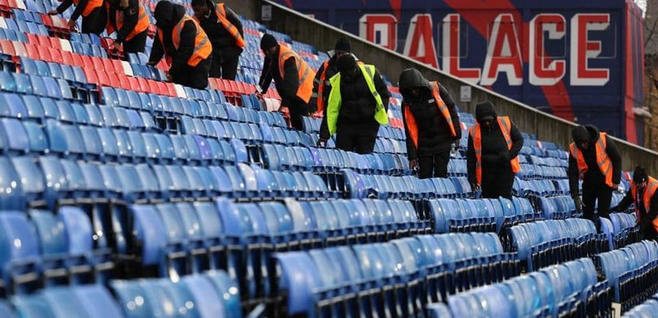 Personal limpiando asientos en el estadio Selhurst Park