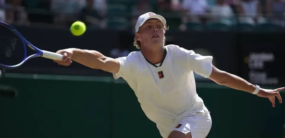Jugador de tenis alcanzando una pelota en Wimbledon