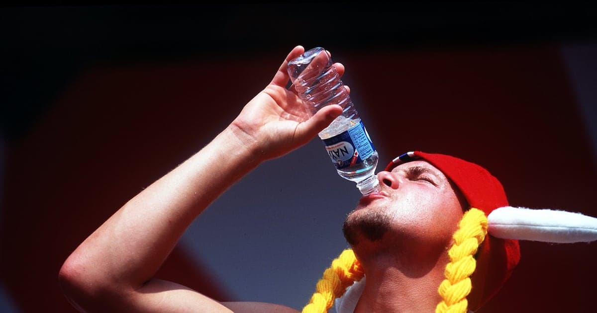 Hombre bebiendo agua de una botella en evento Hombre bebiendo agua de una botella en evento