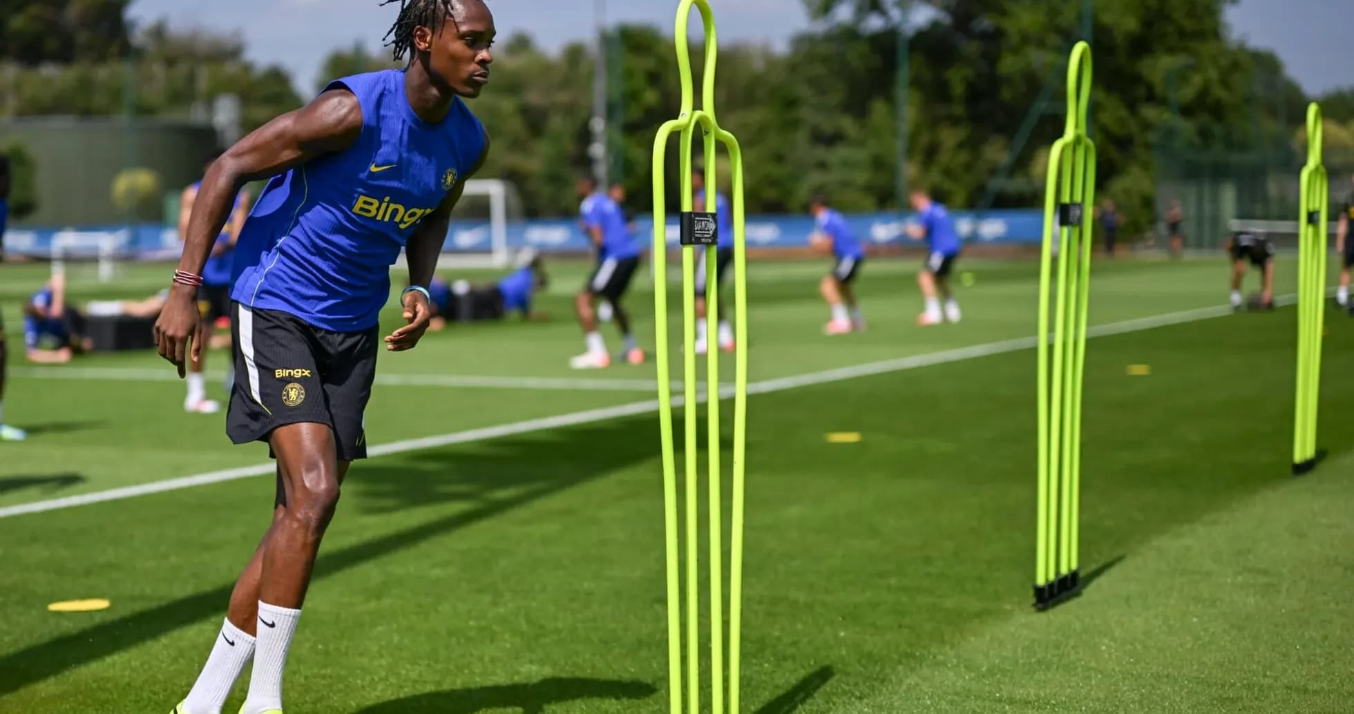 Jugador entrenando en campo con conos de entrenamiento Jugador entrenando en campo con conos de entrenamiento